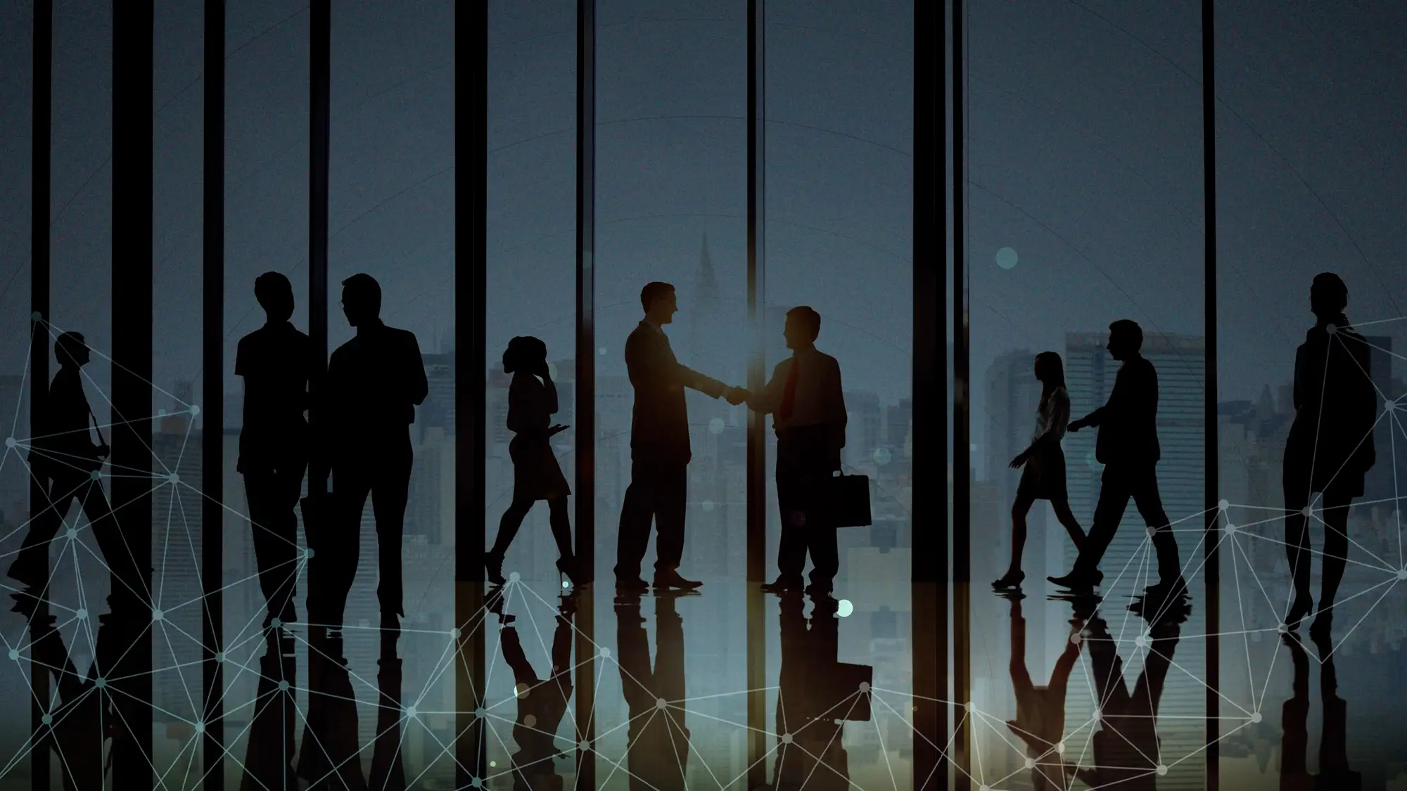 Business professionals silhouettes shaking hands in office lobby