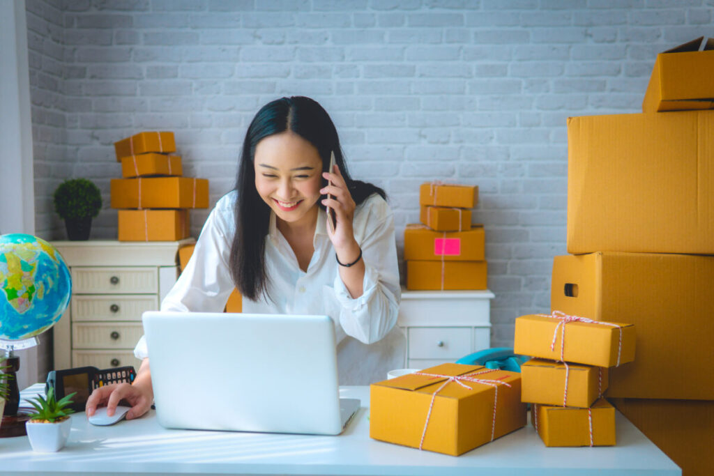 Online seller managing packages while working on laptop